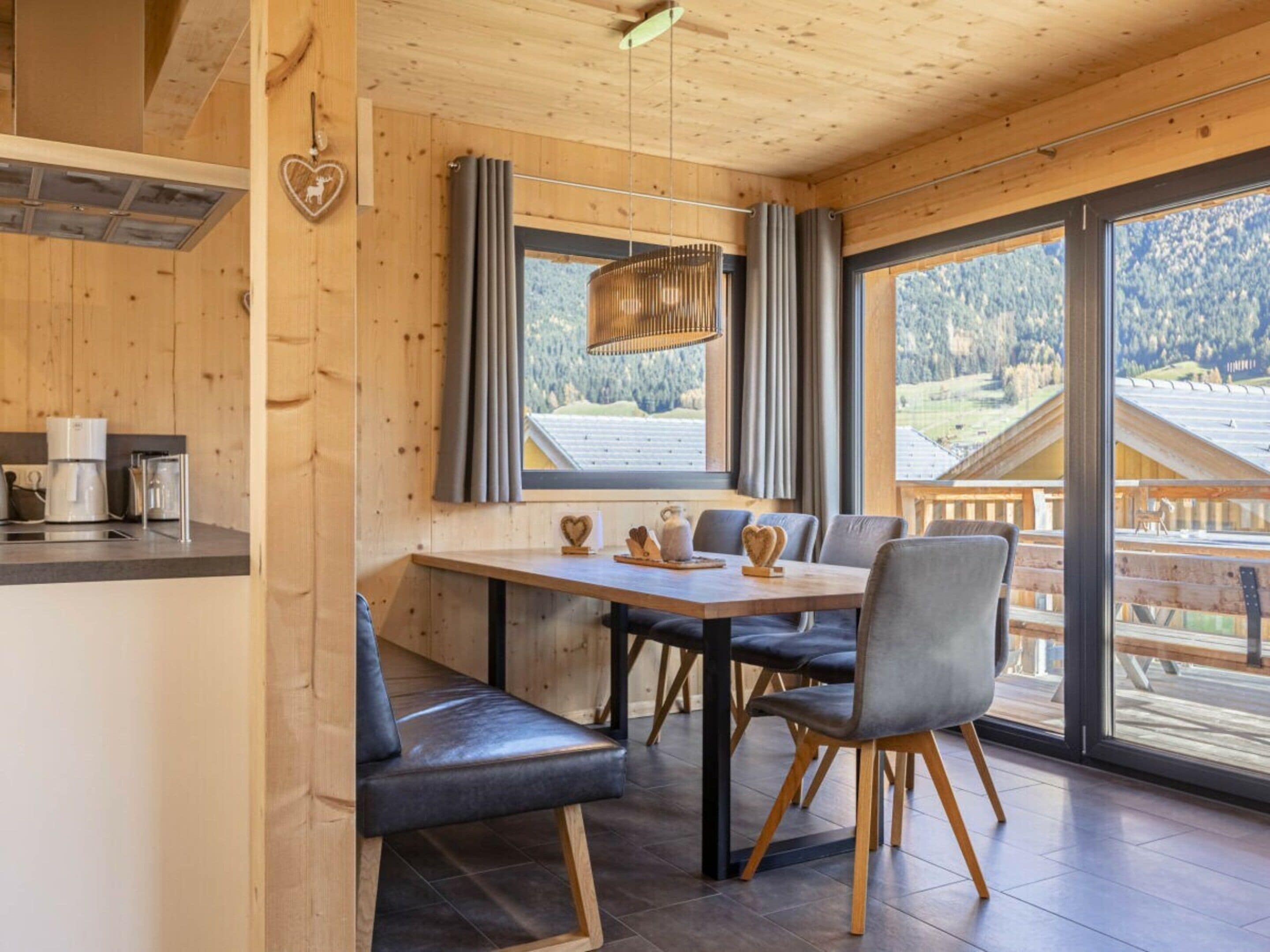 A wooden interior with a dining table, chairs, and a view of the outdoors.
