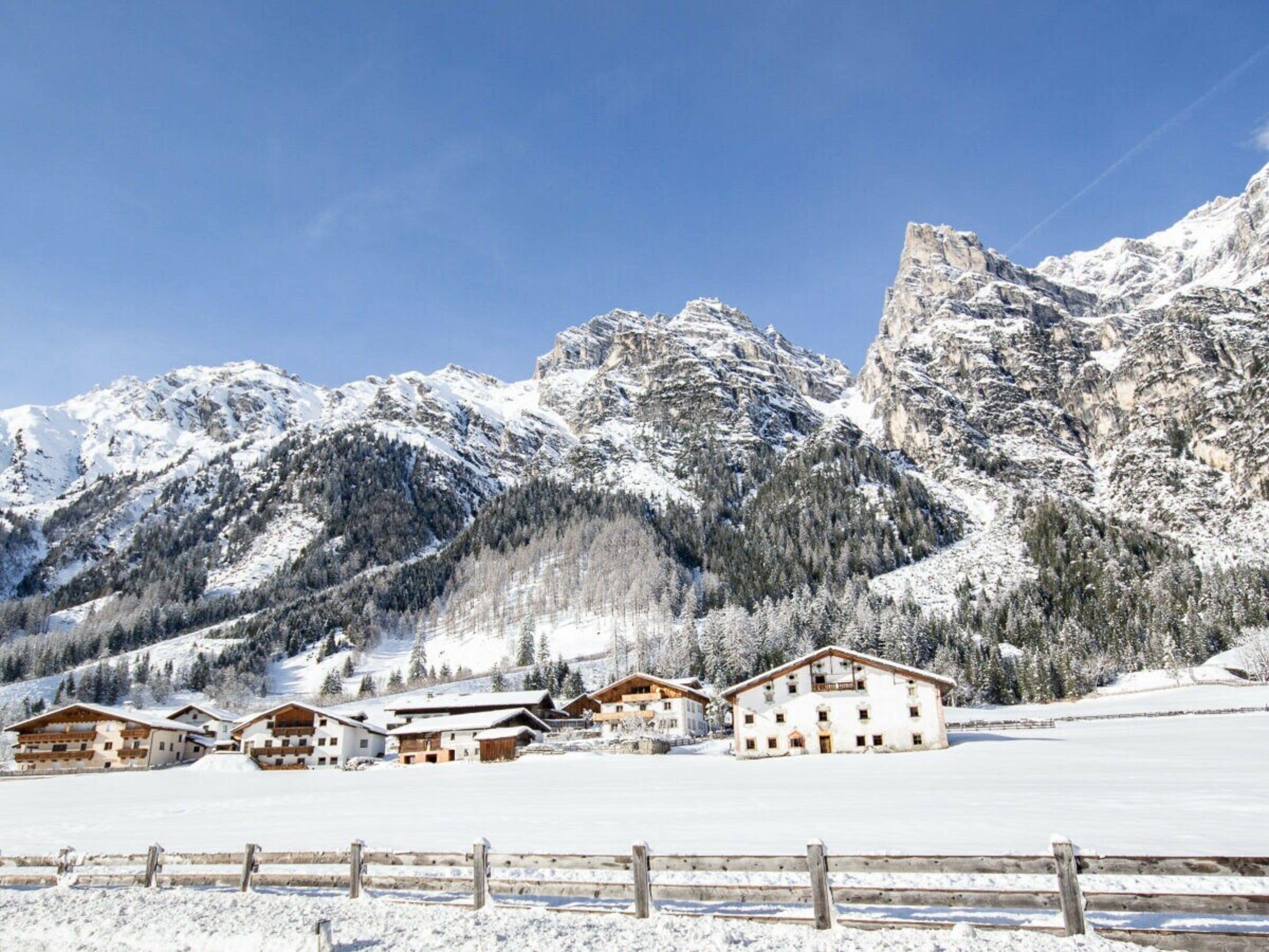 Paesaggio montano innevato con chalet in legno e cielo sereno.