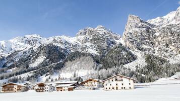 Paesaggio montano innevato con chalet in legno e cielo sereno.