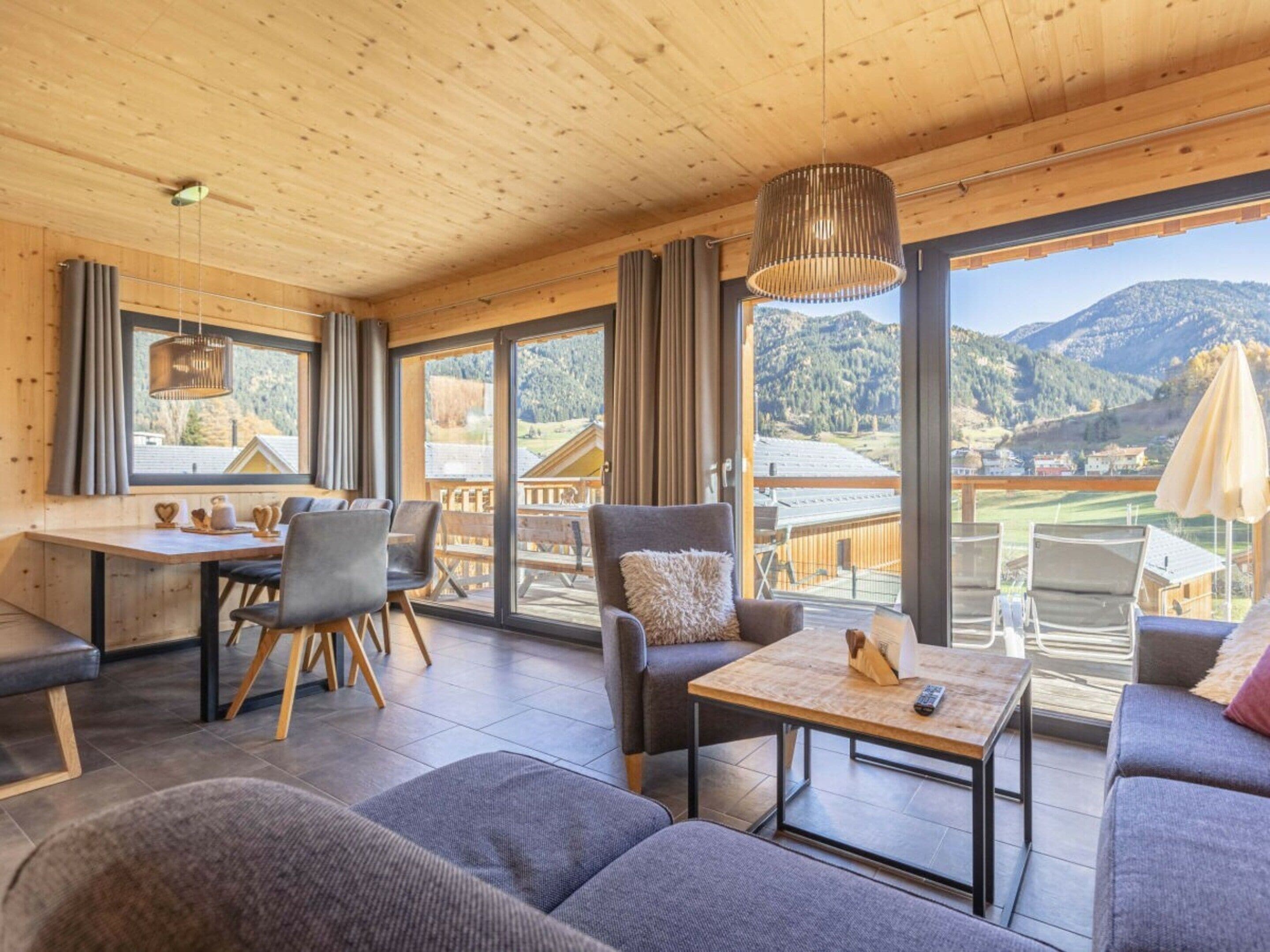 Un interior moderno con zona de comedor, asientos y ventanas amplias con vistas a la montaña.