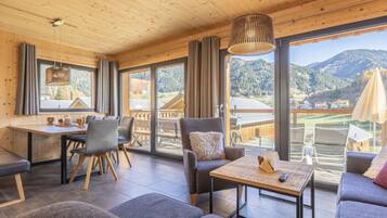 Un interior moderno con zona de comedor, asientos y ventanas amplias con vistas a la montaña.