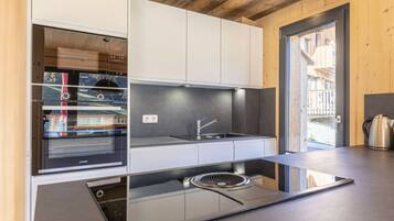 A modern kitchen with a glass cooktop, stainless steel appliances, and wooden cabinetry.