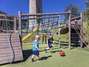 Ein Spielplatz mit einer Seilbrücke, einer Rutsche und einer Kletterkonstruktion.