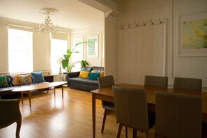 A spacious living room with a wooden dining table, comfortable seating, and a chandelier. - Cozy 3-Bedroom Flat - Fitzrovia & Soho (London)