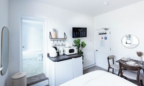 Une chambre d’hôtel moderne dotée d’une kitchenette, d’un coin repas et d’un grand miroir.