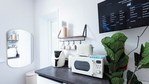 Cozinha moderna com micro-ondas embutido, máquina de café e prateleira com utensílios.