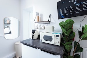 A modern kitchen with a built-in microwave, a coffee machine, and a shelf with utensils. - The Stanley Arms Hotel by Guestz (Seascale)