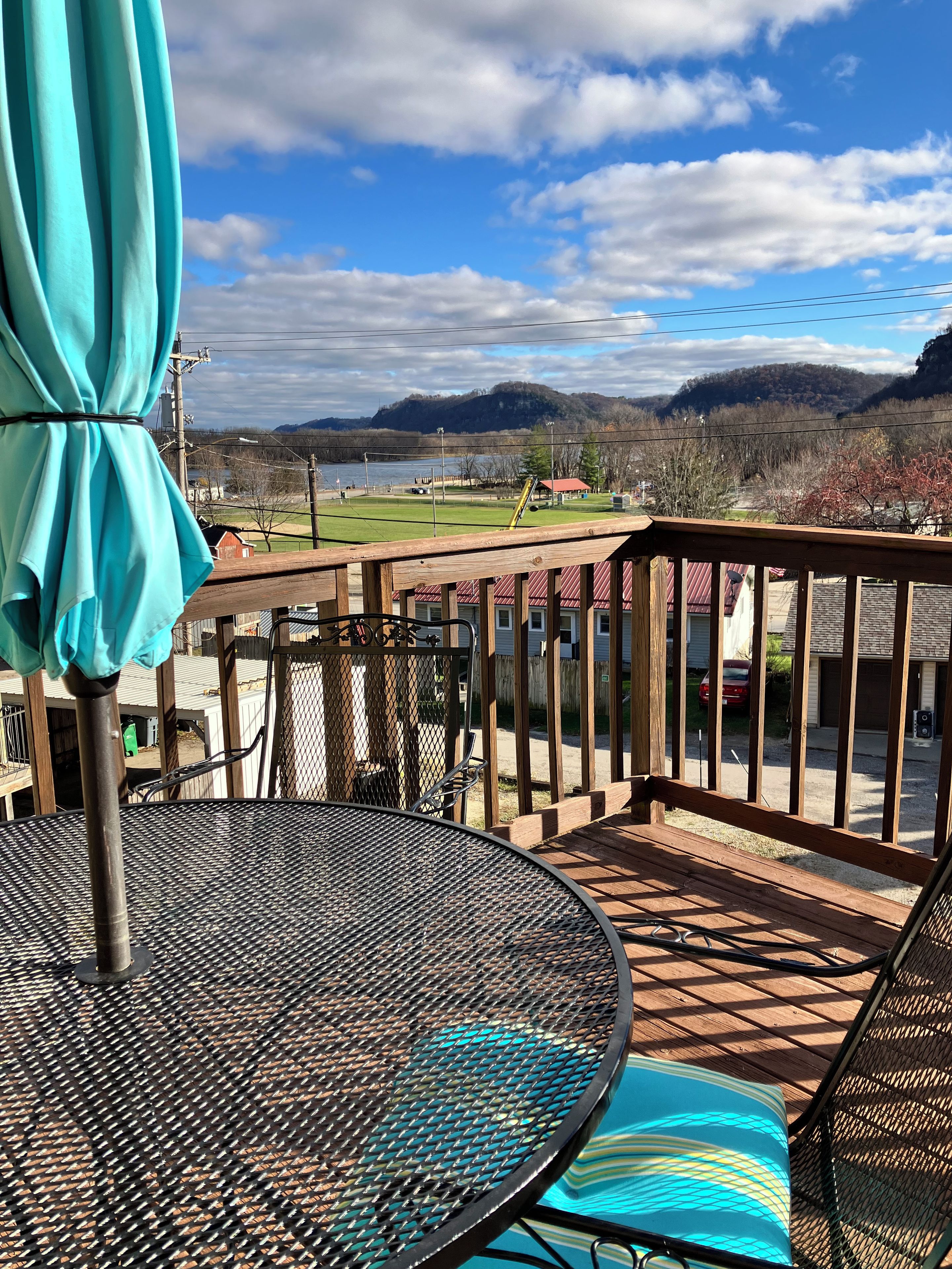 Eine Terrasse mit Metalltisch und -stühlen mit Blick auf einen See und ferne Berge.