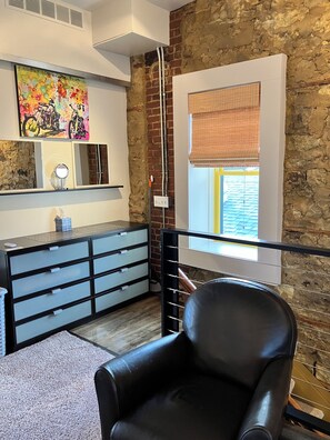 A modern room with a black leather chair, a large mirror, a colorful abstract painting, and a window with a view of the outside. - Spacious house downtown Lansing with 6 king beds. Can sleep up to 17 guests. (Lansing)