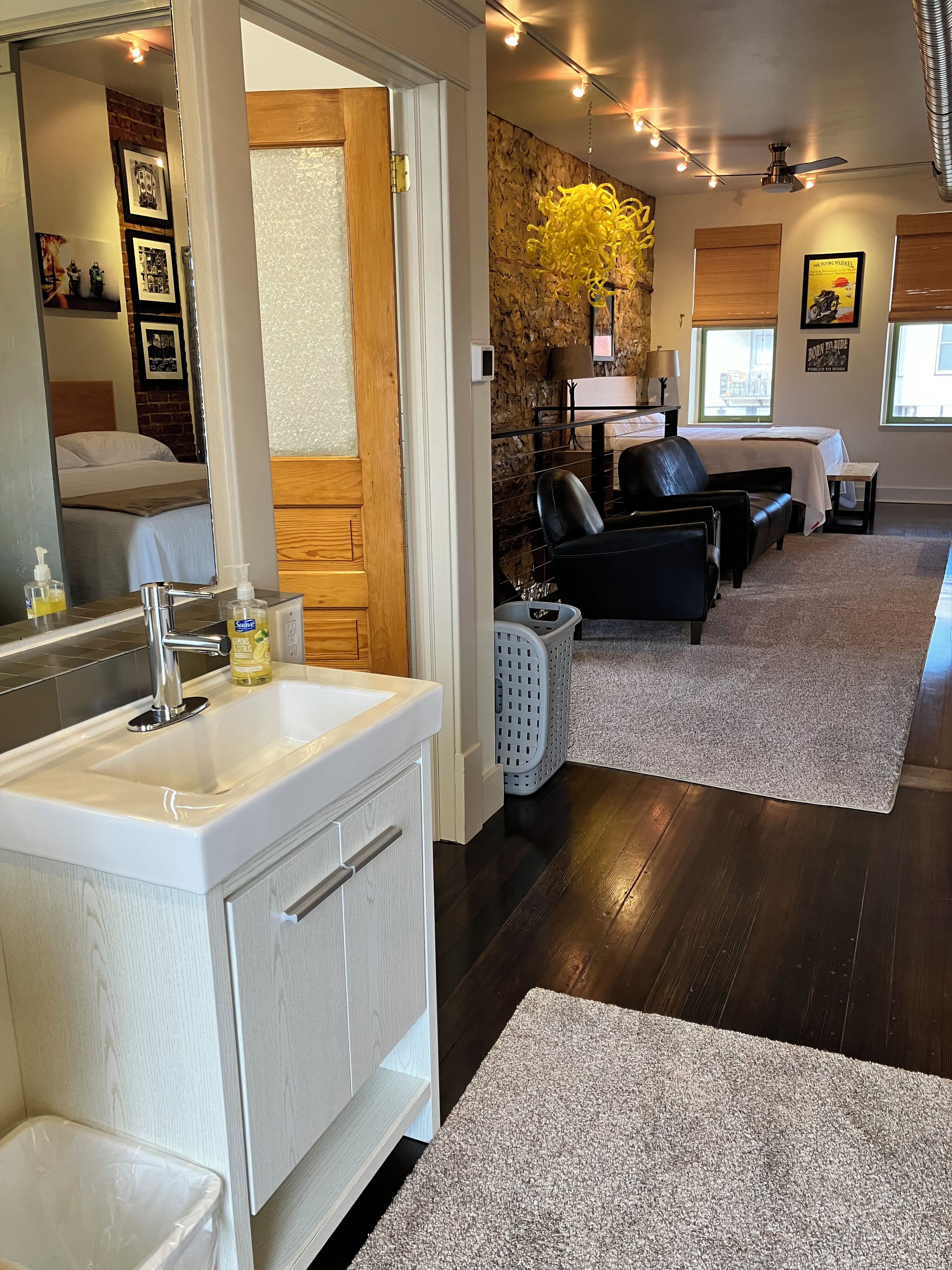 A modern bathroom with a large mirror, white sink, and wooden cabinetry.