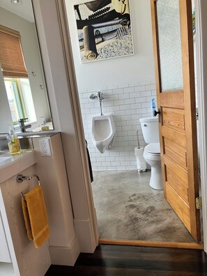 Un baño con orinal, inodoro y una puerta de madera.