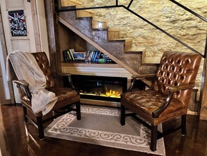 A cozy living area with leather armchairs, a fireplace, and a bookshelf. - Spacious home downtown with 6 king beds. Sleeps up to 17 guests, outdoor shower. (Lansing)