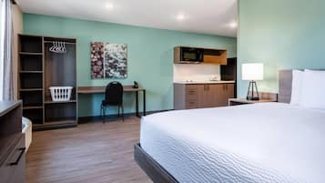 A hotel room with a bed, a desk, a kitchenette, a wardrobe, and a bathroom.