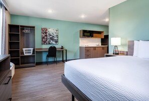 Habitación de hotel con cama, escritorio, kitchenette, armario y baño.