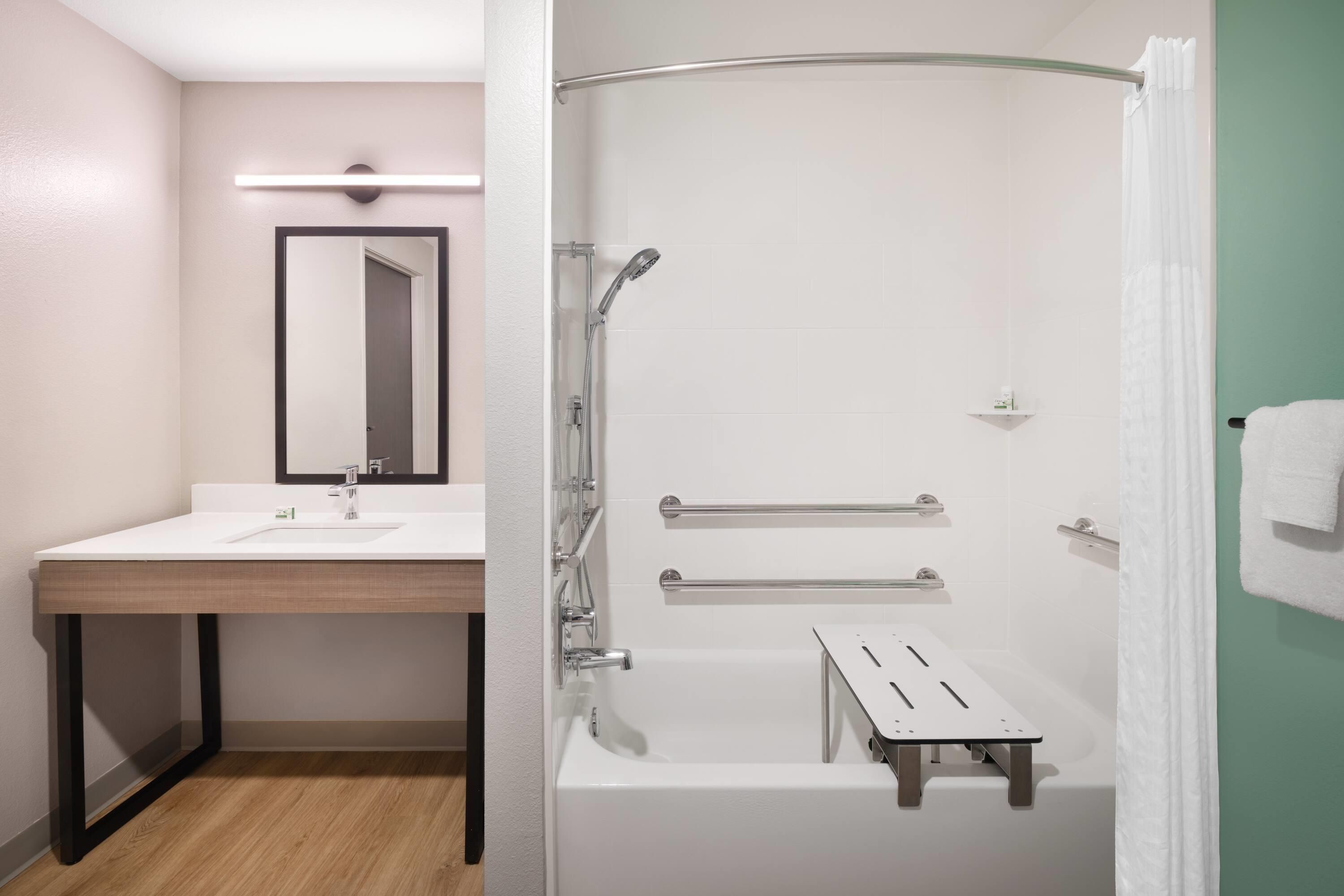 A bathroom with a sink, mirror, shower, and bathtub.