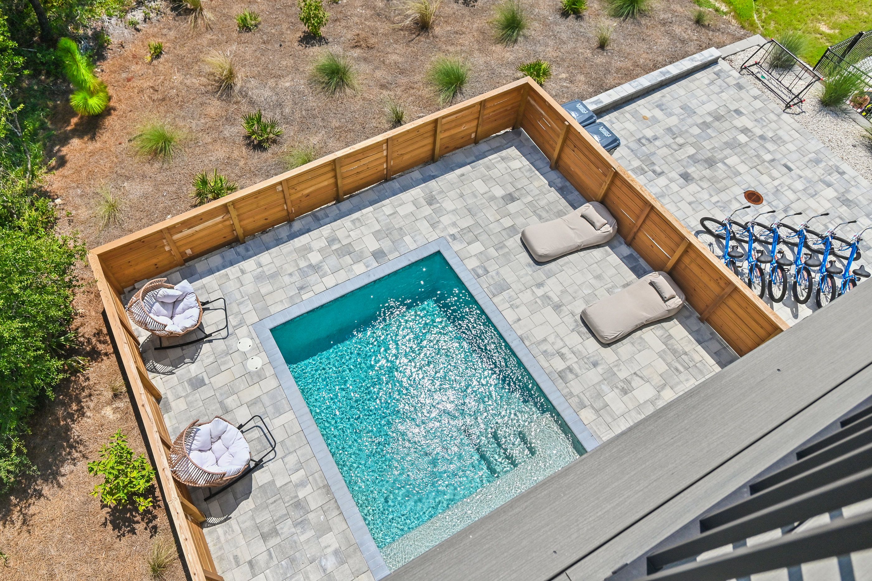A rooftop pool area with a rectangular pool, lounge chairs, and a bike rack.