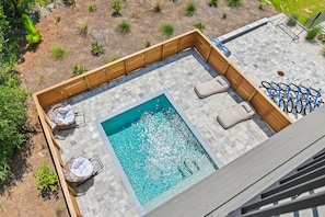 Un espace piscine aménagé sur le toit, comprenant une piscine rectangulaire, des chaises longues et un porte-vélos.