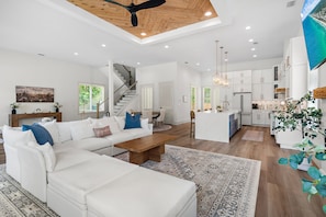 A spacious living room with a large white sectional sofa, a wooden coffee table, and a patterned rug. - Pet Friendly | Bikes | Golf Cart | Private Pool | Spotted Dolphin (Santa Rosa Beach)