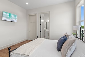 A bedroom with a bed, a television on the wall, a window, and a door leading to a bathroom. - Pet Friendly | Bikes | Golf Cart | Private Pool | Spotted Dolphin (Santa Rosa Beach)