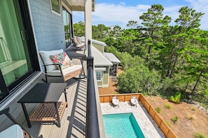A balcony with outdoor furniture, a pool, and a view of the surrounding greenery. - Pet Friendly | Bikes | Golf Cart | Private Pool | Spotted Dolphin (Santa Rosa Beach)