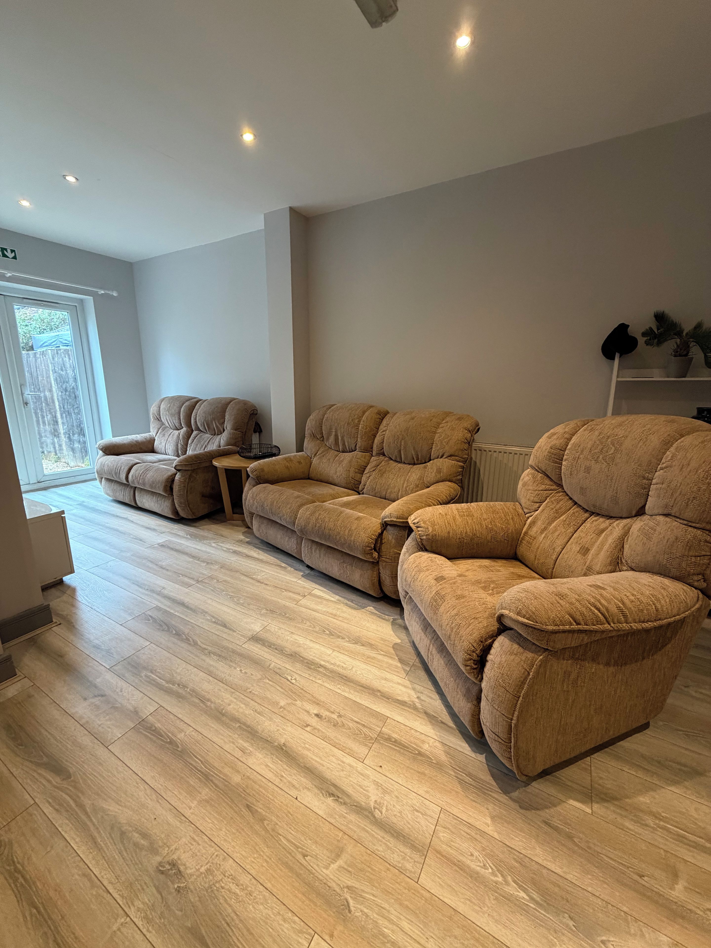 A living room with a sectional sofa, a small table, and a radiator.