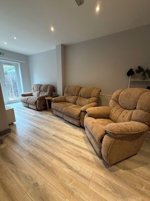 Ein Wohnzimmer mit einem Ecksofa, einem kleinen Tisch und einer Heizung.