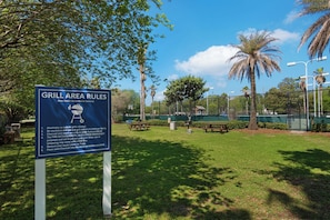 A sign with grill area rules in a park with picnic tables and palm trees. - 🌴Beach Nearby + Lagoon Pool | Fab Amenities | Palms Resort 1404☀️ (Destin)