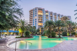 A hotel with a swimming pool, palm trees, and a blue-roofed building. - 🌴Beach Nearby + Lagoon Pool | Fab Amenities | Palms Resort 1404☀️ (Destin)