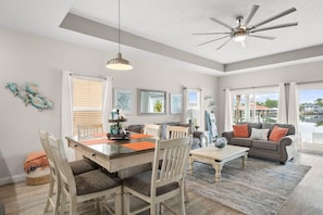 A spacious living area with a dining table, chairs, a sofa, and a ceiling fan. - 🎣Angler Dock House | Private Pool | Lagoon View | Close to Beach🌊 (Panama City Beach)