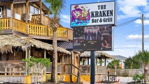 A wooden building with a sign for 'The Kraken Bar & Grill' featuring a pirate ship illustration. - 🎣Angler Dock House | Private Pool | Lagoon View | Close to Beach🌊 (Panama City Beach)