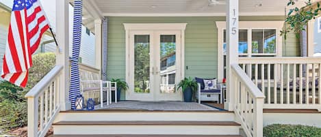 A front porch with a set of wooden steps leading to a door, a flag, and a mailbox.