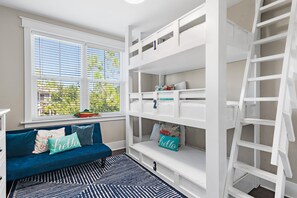 A room with bunk beds, a sofa with cushions, a window with blinds, and a ladder. - 🌴Sea Esta | 4BR Coastal Retreat | Golf Cart + 6 Bikes | NatureWalk🌴 (Santa Rosa Beach)