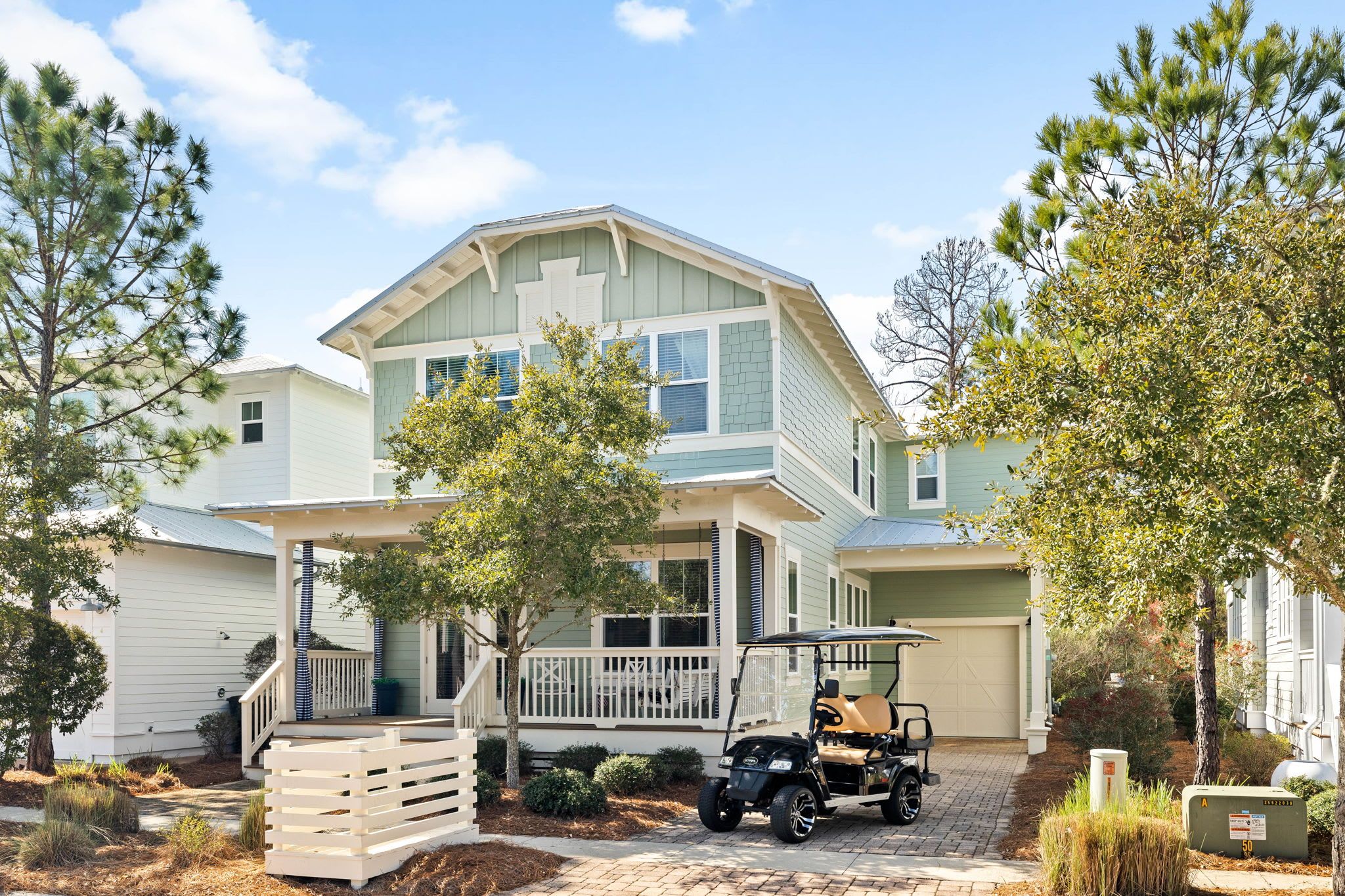 A two-story house with a porch, a covered driveway, and a golf cart parked in front.