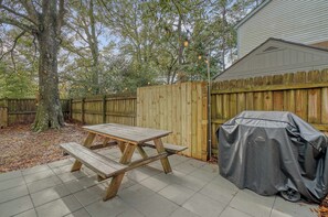 Un patio trasero con una mesa de picnic, una parrilla y una valla de madera.