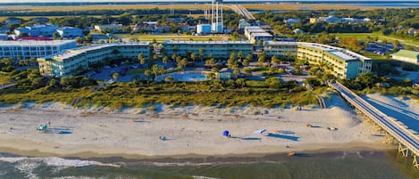 A coastal hotel with multiple buildings, a beach, and a pier.