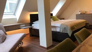 Une chambre avec un plafond en pente, un lit, un bureau et une chaise.