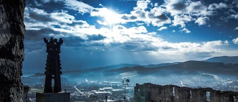 Una estructura de torre histórica con vistas a un paisaje urbano y montañas al fondo.