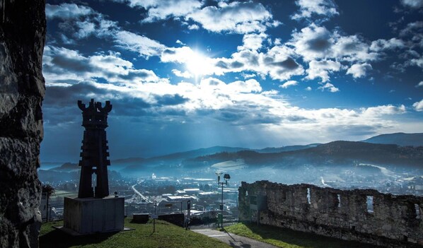 A historical tower structure with a view of a cityscape and mountains in the background. - Hotel Braun (Voitsberg)