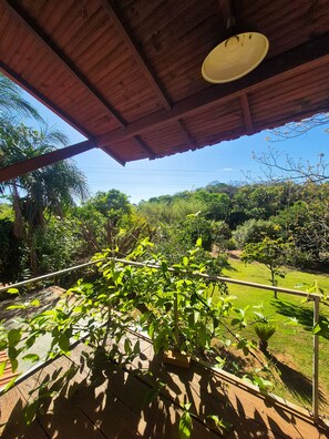 A covered outdoor area with a wooden ceiling and a view of a lush green landscape.