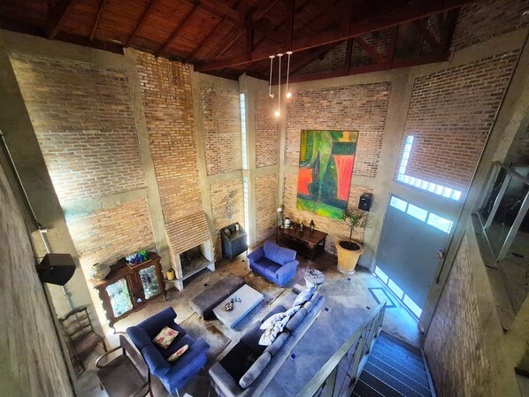 Un loft espacioso con paredes de ladrillo visto, un cuadro abstracto grande y un nivel superior con asientos.