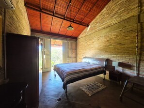 A bedroom with a bed, a desk, a chair, and a large window with shutters.