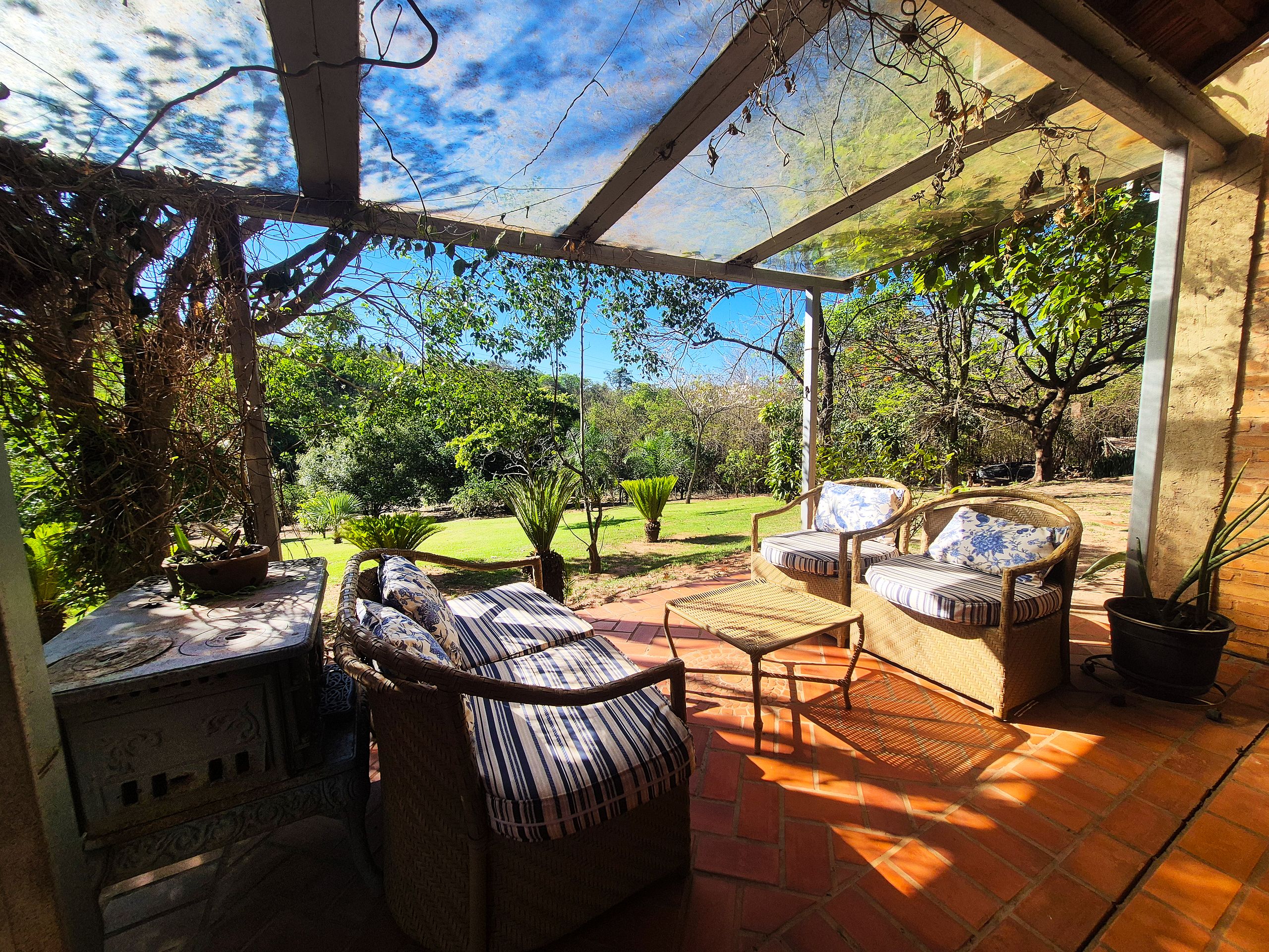A covered patio with wicker furniture, a small table, and potted plants.
