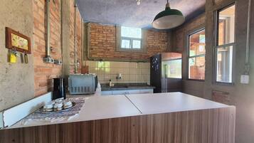 Uma cozinha com paredes de tijolo, bancada de madeira, torradeira antiga e geladeira.