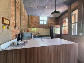 Una cocina con paredes de ladrillo, encimera de madera, una tostadora antigua y un refrigerador.