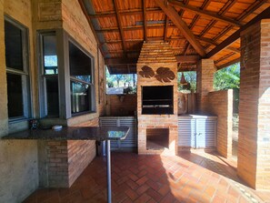An outdoor kitchen area with brick walls, a wooden ceiling, and a brick floor.