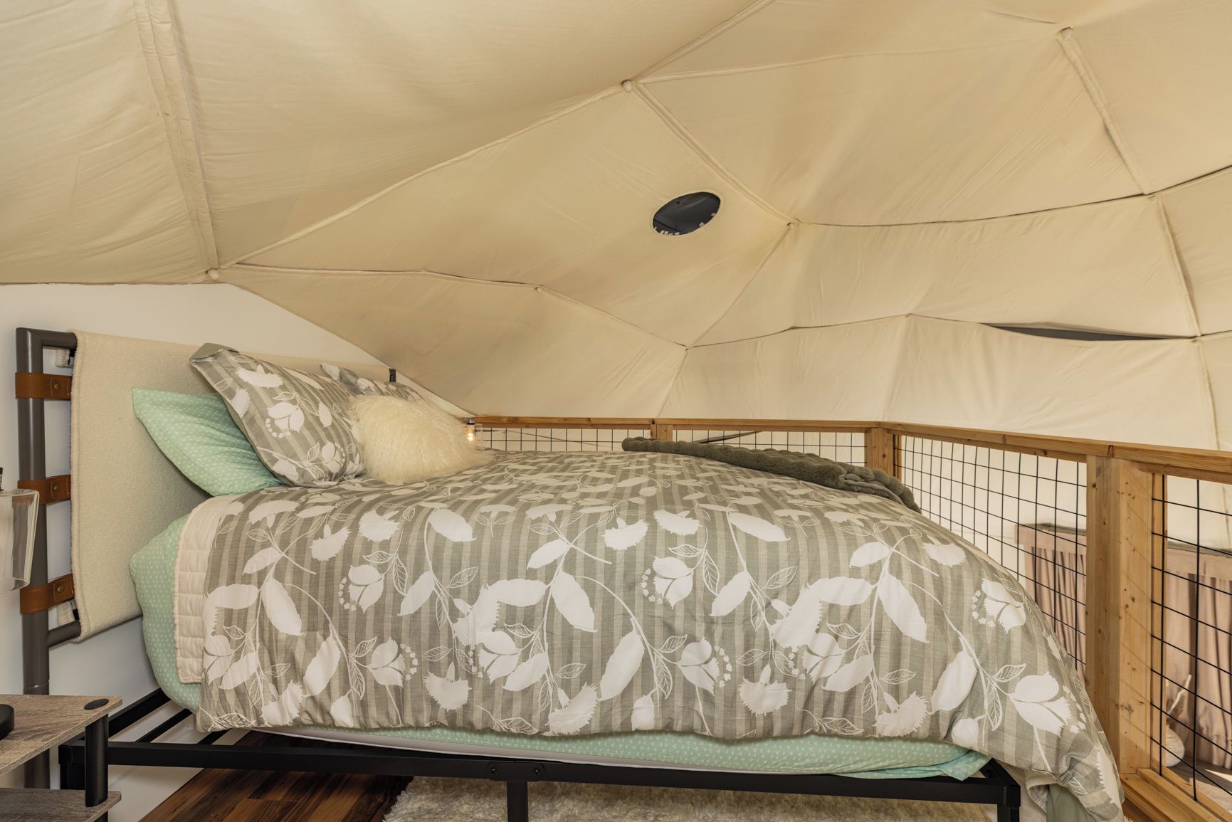 A tented room with a bed, a wooden ladder, and a small table.