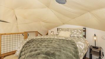 A cozy tented room with a bed, a small table, and a lamp.