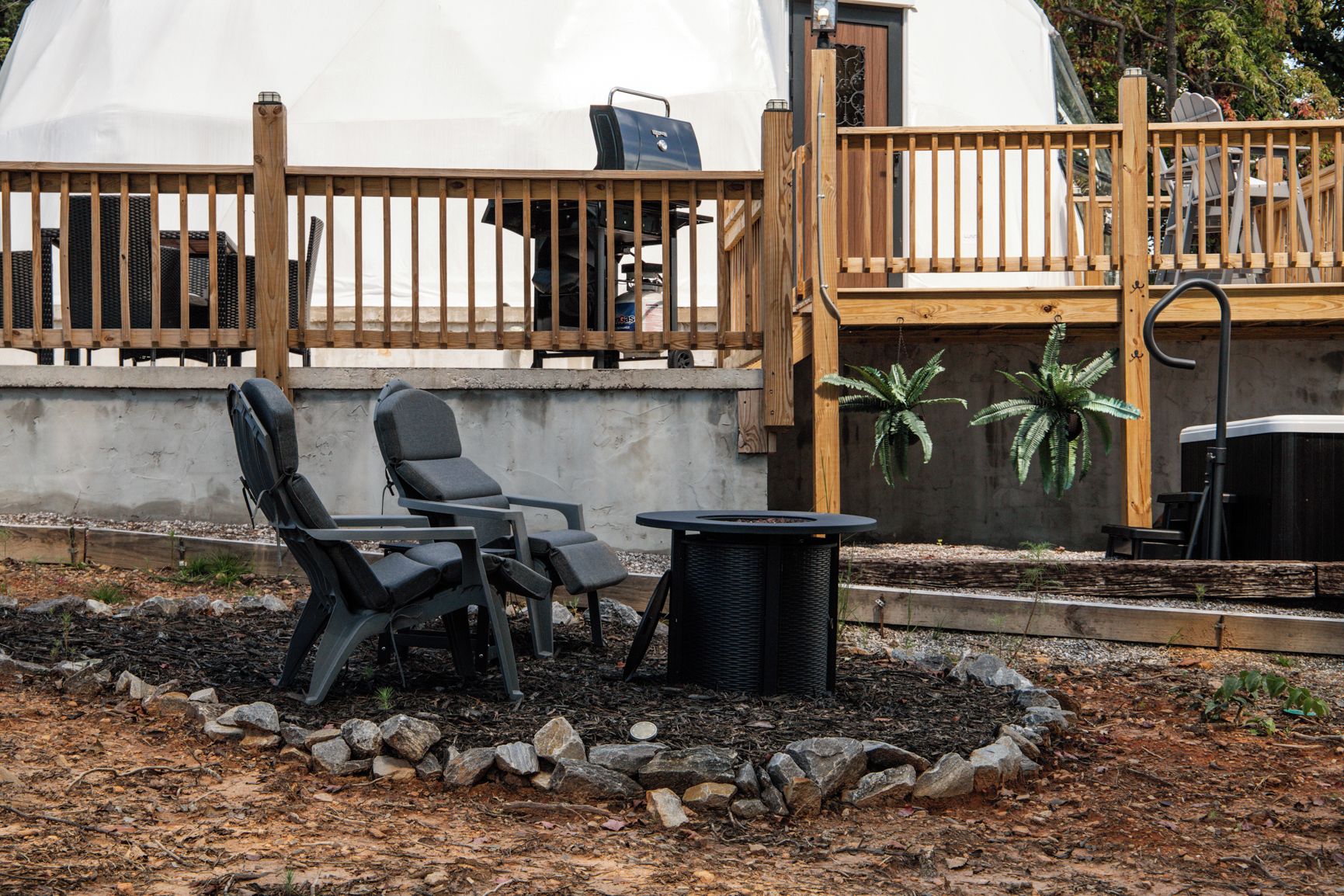 Een buitenruimte met twee stoelen, een tafel en een barbecue.