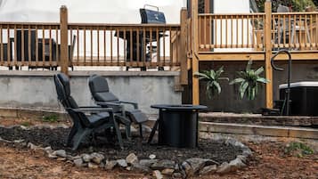 Een buitenruimte met twee stoelen, een tafel en een barbecue.