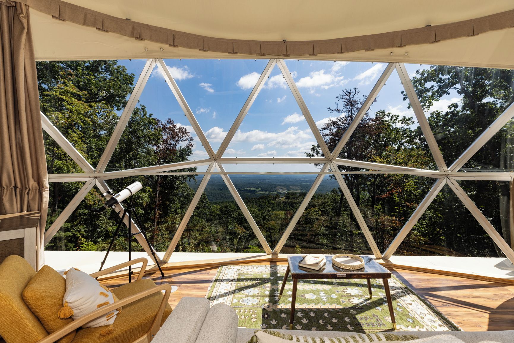 A room with a large window offering a panoramic view of a forested landscape.